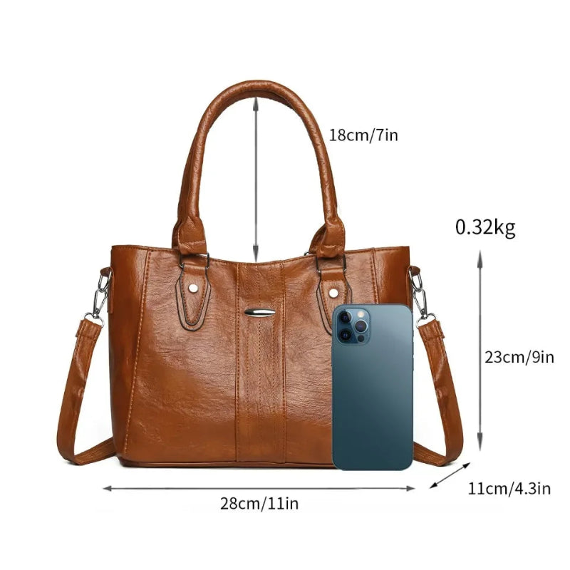 Brown handbag with measurements and a phone for scale on a white background