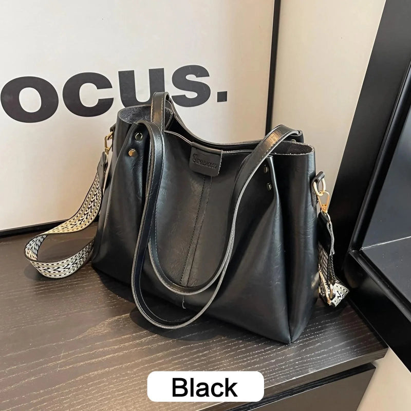 Black handbag on a wooden surface with 'OCUS' branding in the background.