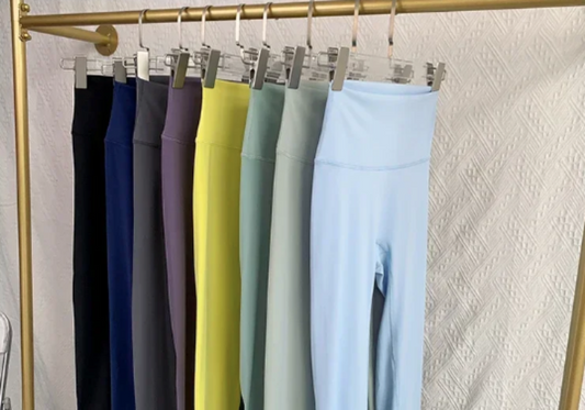 Colorful leggings hanging on a rack against a textured wall.