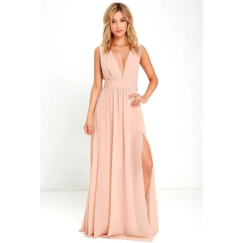 Woman wearing a long, light pink dress with a slit on a white background
