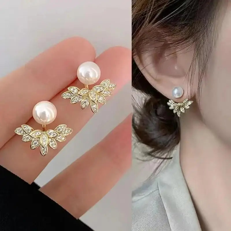 Pearl earrings with gold leaves held in hand and worn on ear