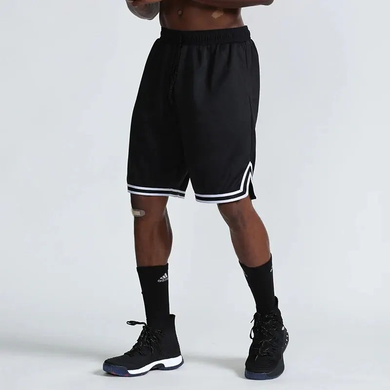 Person wearing black shorts with white trim on a plain background