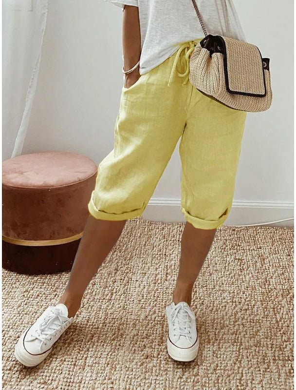 Person wearing yellow shorts, white sneakers, and a beige bag on a carpeted floor.