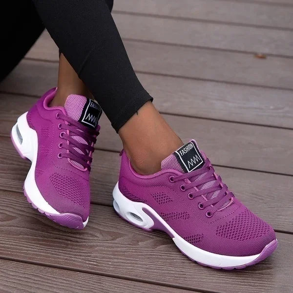 Purple sneakers with white soles on a wooden floor