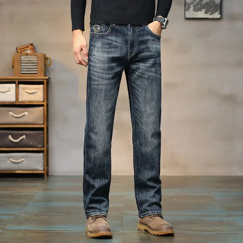 Person wearing blue jeans standing in a room with wooden drawers in the background