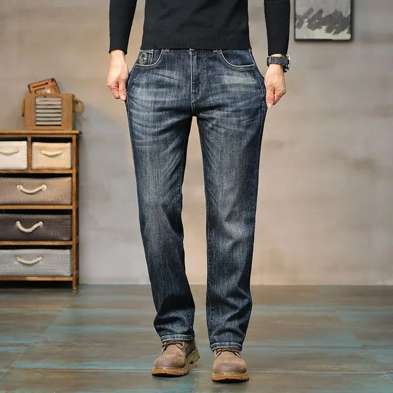 Person wearing blue jeans standing in a room with a wooden cabinet and abstract painting.