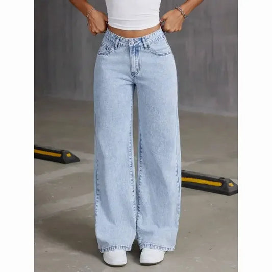 Person wearing light blue wide-leg jeans and a white crop top in an urban setting.