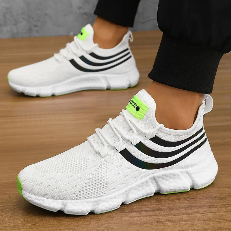 White sneakers with black stripes and green accents on a wooden floor.