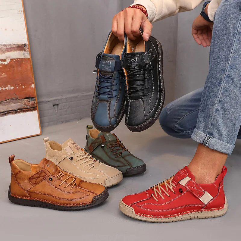 Person holding a pair of black shoes with other colored shoes on the ground.