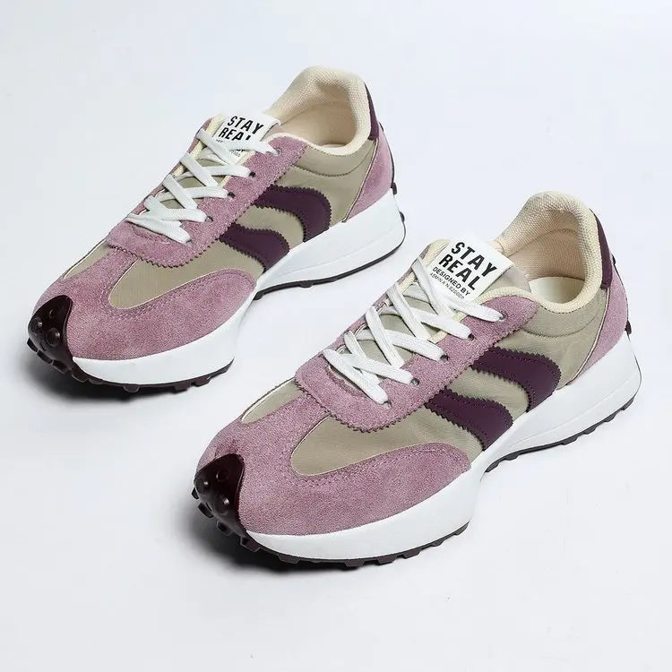 Pair of pink and beige sneakers with white laces on a light gray background