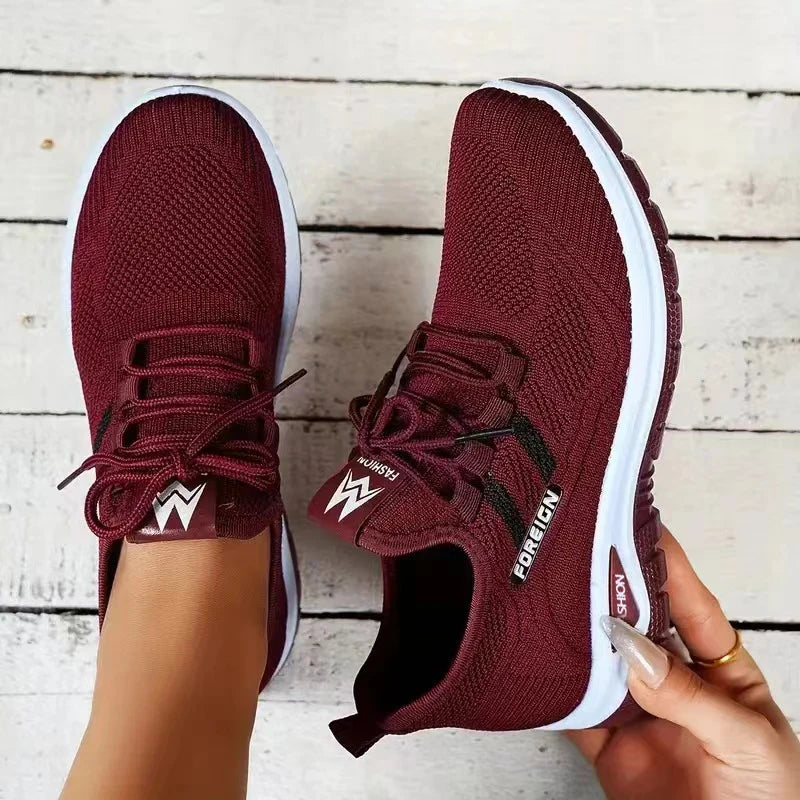 Maroon running shoes with white soles on a wooden floor