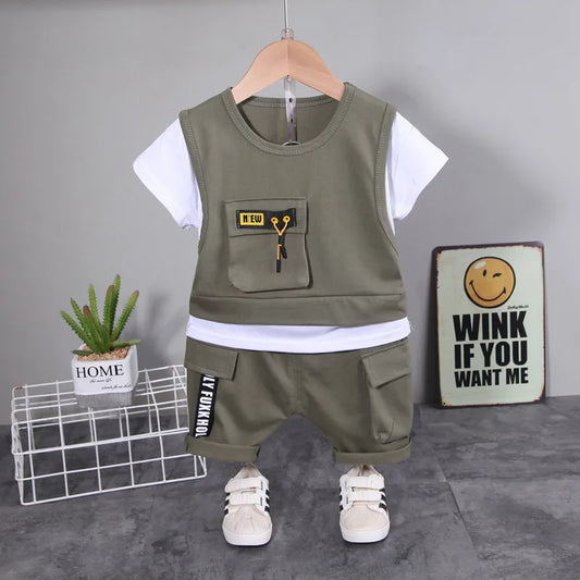 Children's green and white outfit with shorts on a hanger against a gray background.