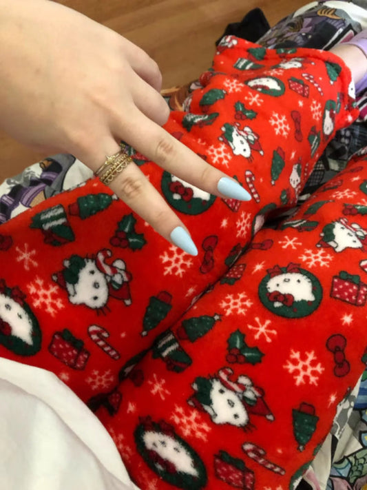 Red fabric with Christmas patterns, including snowmen and snowflakes, held by a hand.