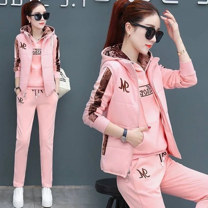 Woman wearing a pink tracksuit with a logo, posing against a gray background.