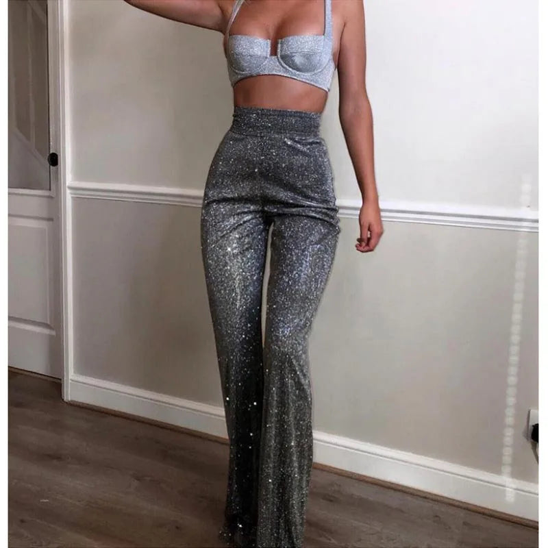 Person wearing sparkly silver top and pants in a room with wooden floor and white walls.