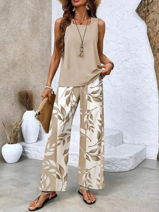 Woman wearing a beige sleeveless top and leaf-patterned pants, standing against a neutral background.