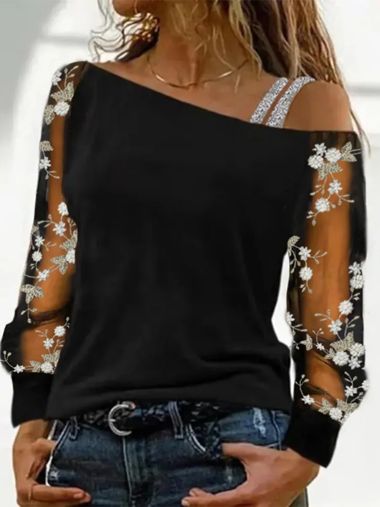 Black top with floral lace sleeves worn by a person on a white background