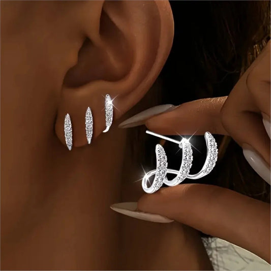 Close-up of a person wearing silver earrings with a dark background