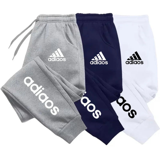 Three pairs of Adidas tracksuits in gray, navy, and white on a white background.