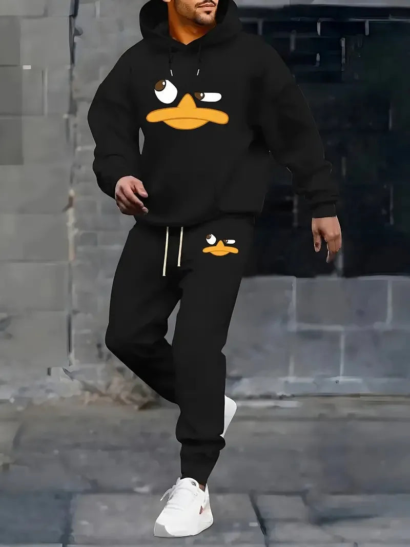 Person wearing a black hoodie and pants with cartoon duck design against a gray brick wall.