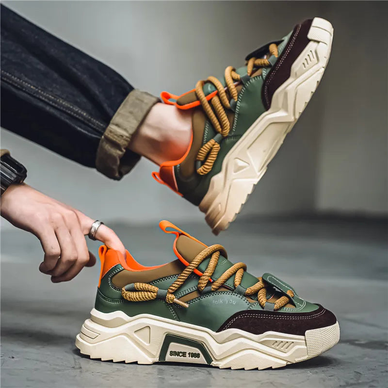 Person wearing and adjusting a green and brown sneaker with orange accents on a gray background
