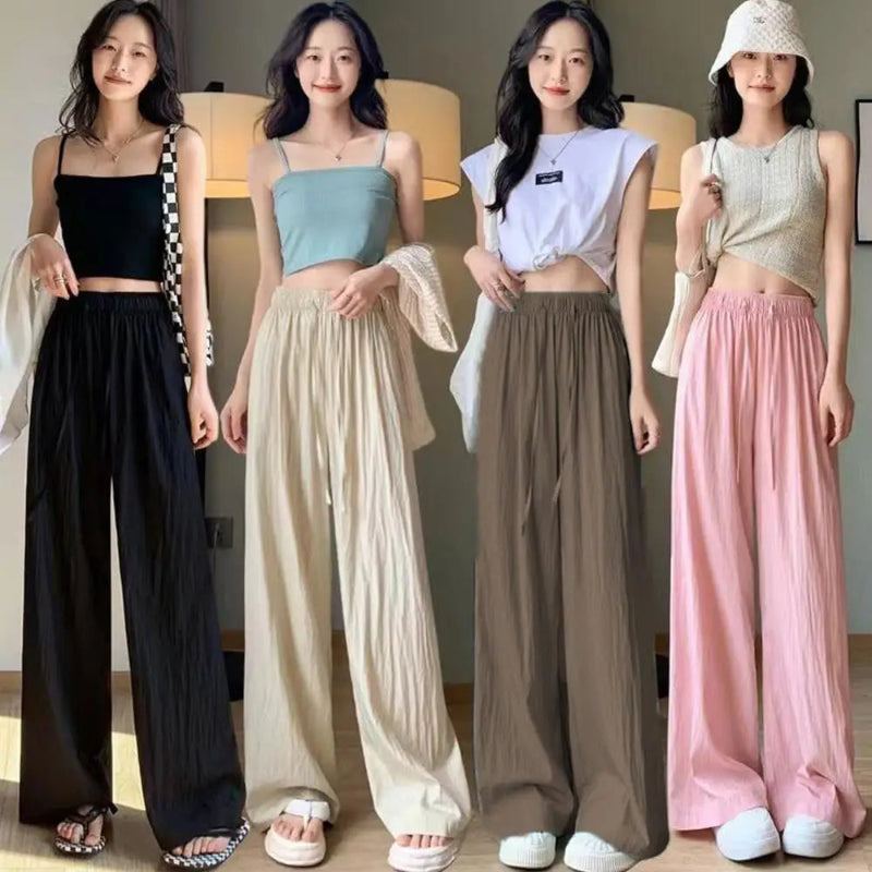 Four women wearing different colored tops and wide-leg pants indoors.