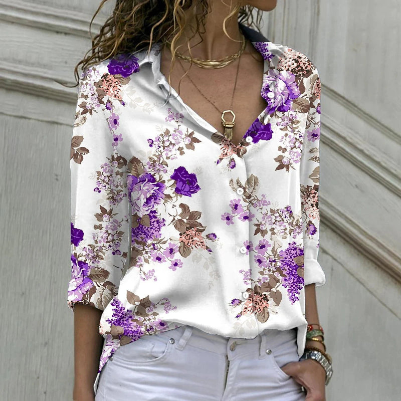 Woman wearing a white blouse with purple floral patterns against a neutral background