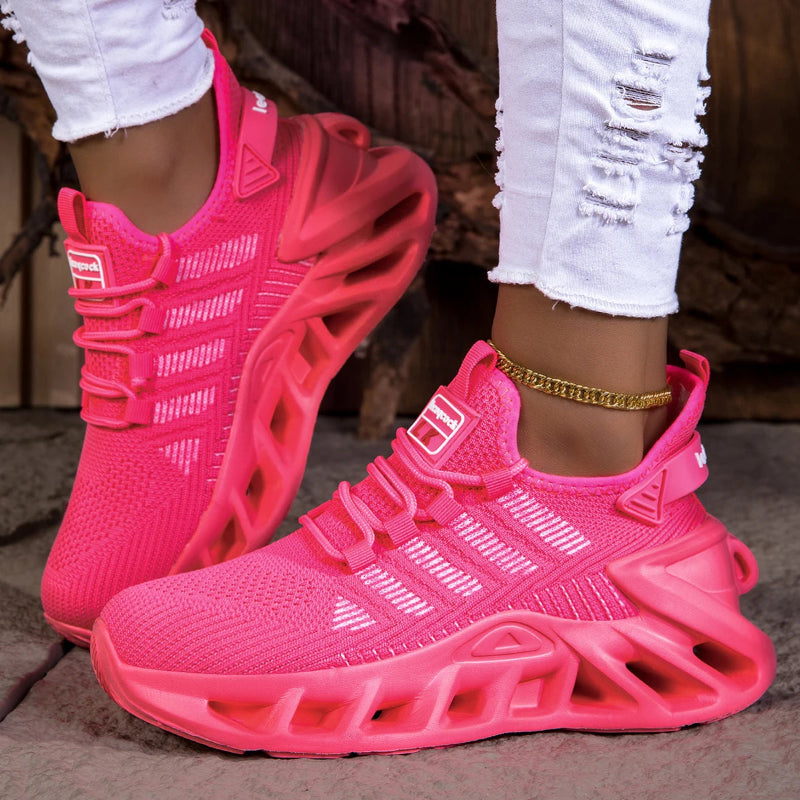 Pink sneakers worn with white pants on a neutral background