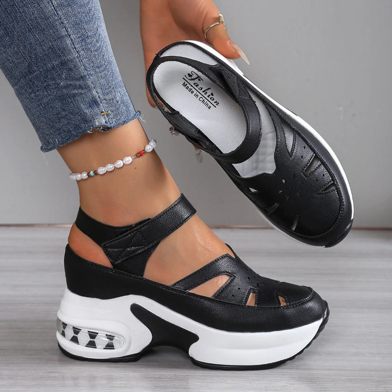 Black and white sandals worn with jeans on a neutral background