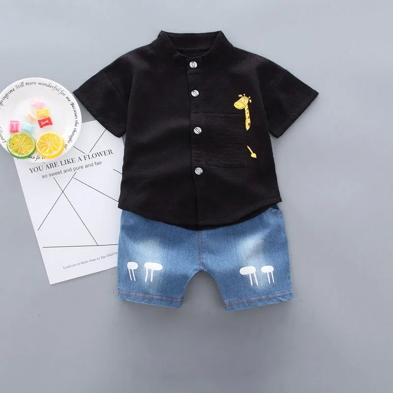 Black shirt with a yellow giraffe design and denim shorts on a gray background