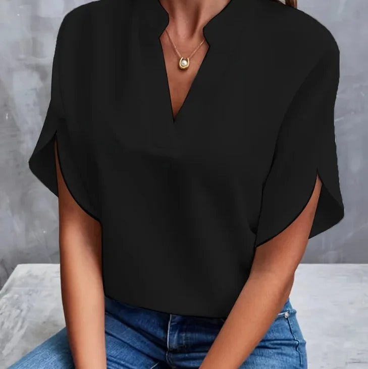 Person wearing a black top and blue jeans against a gray background
