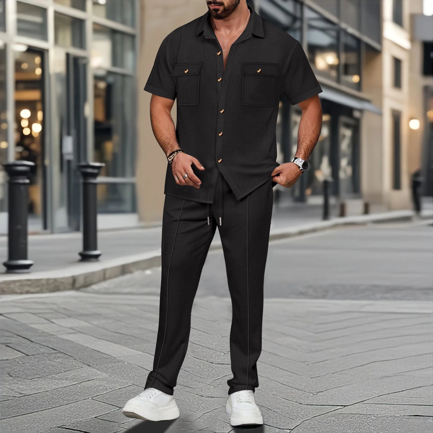 Man wearing a black outfit with white sneakers on a city street.