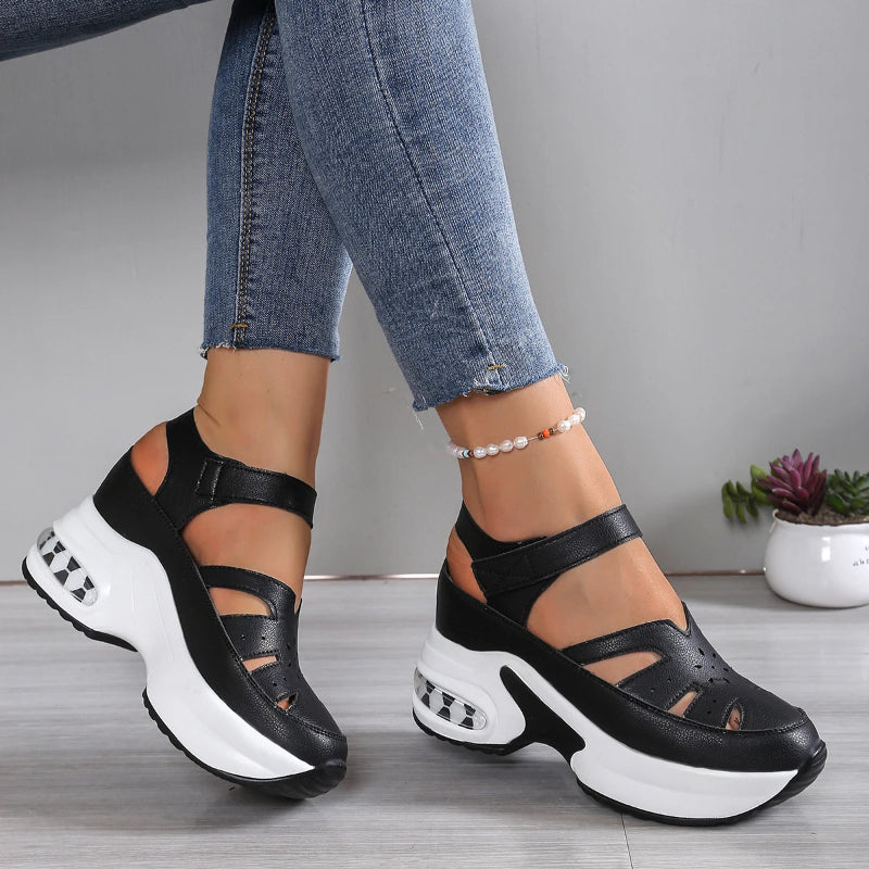 Black and white sandals worn with blue jeans on a neutral background