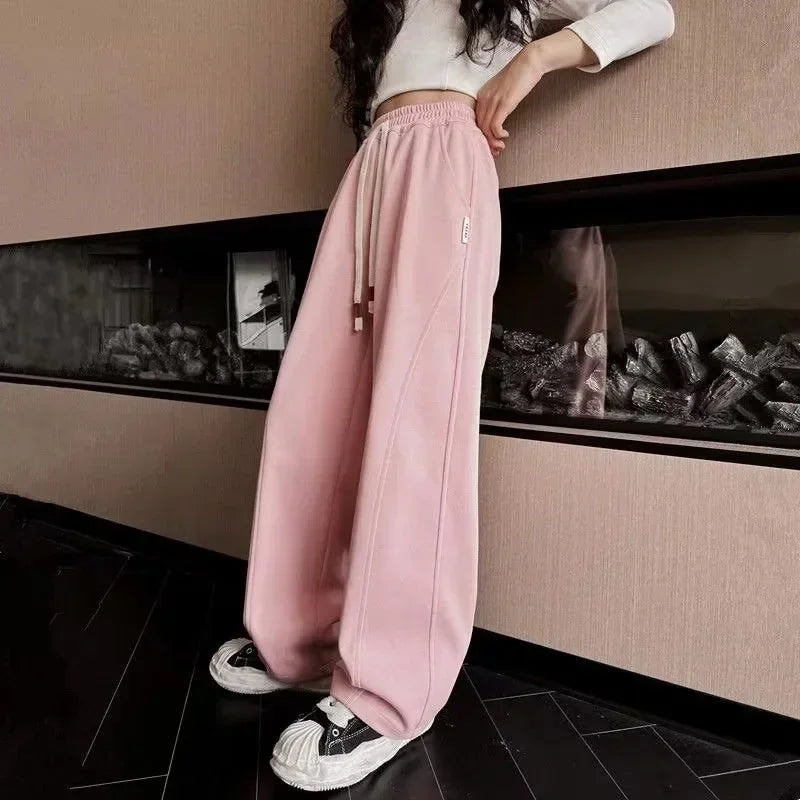 Person wearing pink pants and white sneakers in a room with a fireplace.