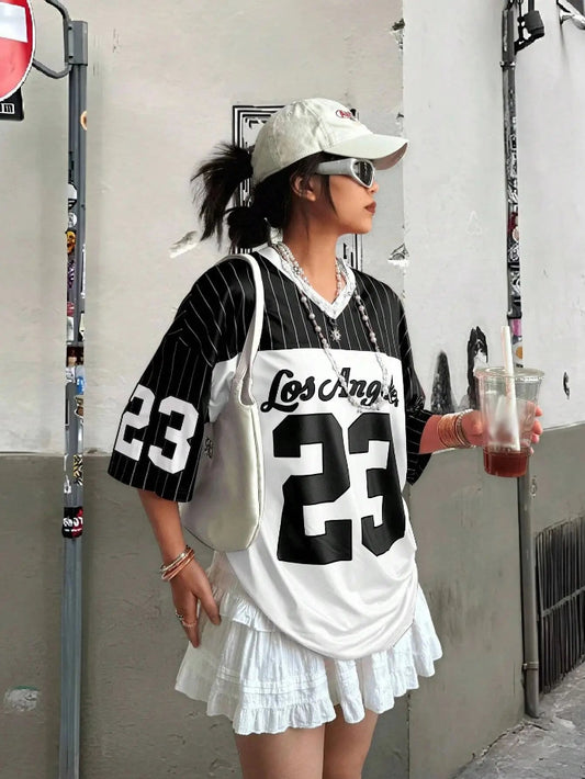 A person wearing a white V-neck T-shirt with the number 23 printed in black, paired with a white skirt, white hat, and holding a drink.