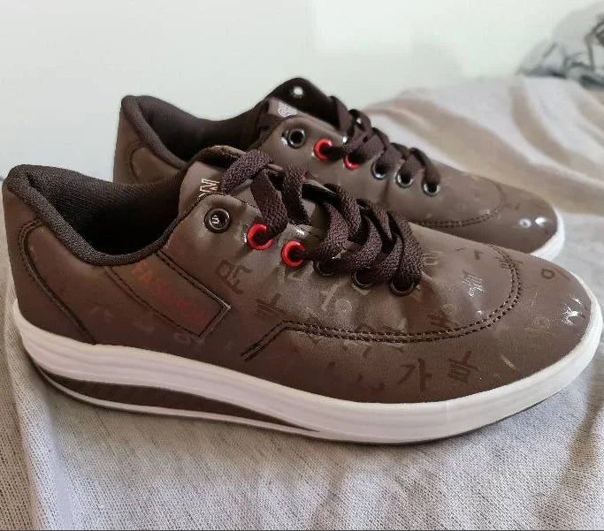 Brown sneakers with red laces on a light fabric surface