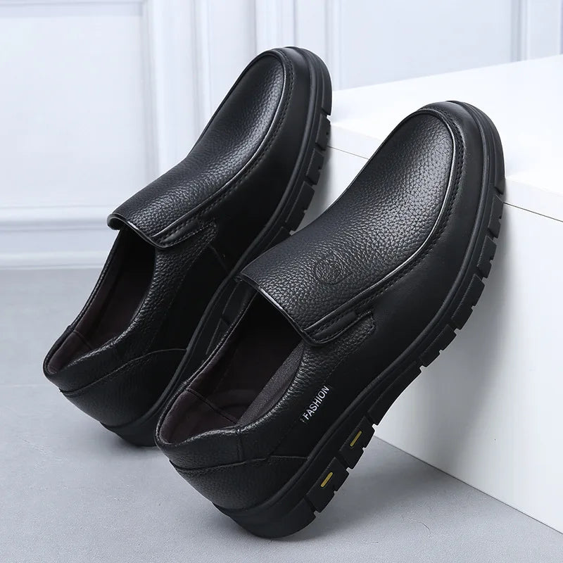 Pair of black leather shoes on a light gray surface with a white background