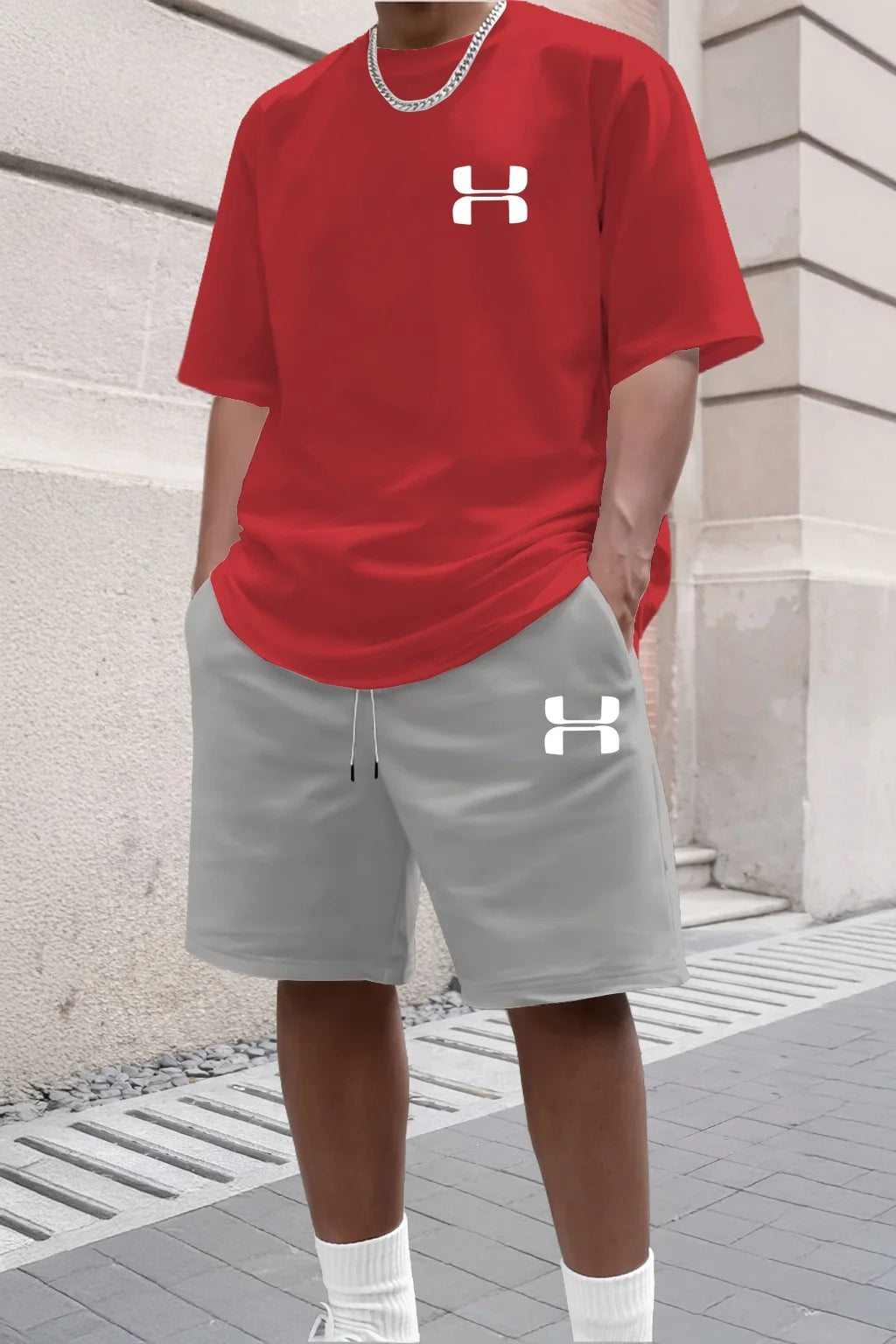 Person wearing a red Under Armour t-shirt and gray shorts with a building in the background