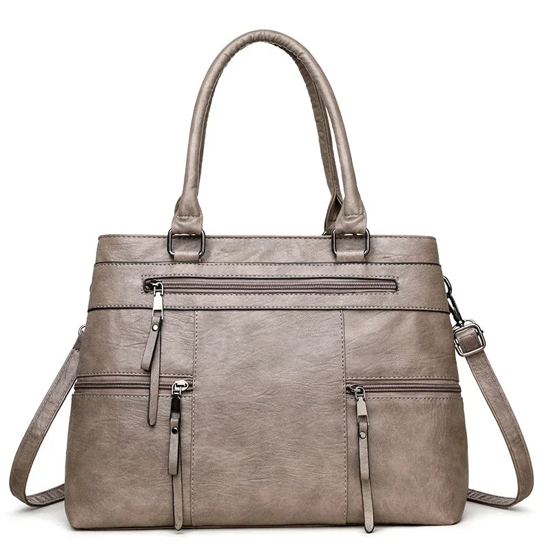 Gray handbag with multiple zippers on a white background