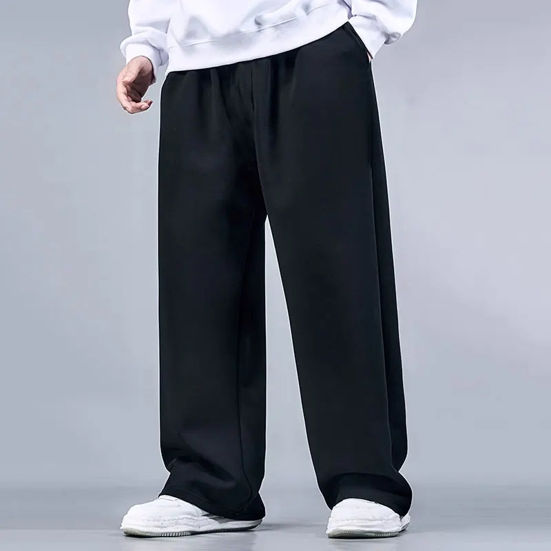 Person wearing black wide-leg pants and white shoes on a gray background