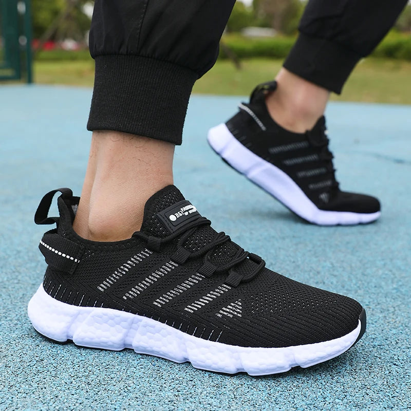 Black athletic shoes with white soles worn by a person on a blue surface.