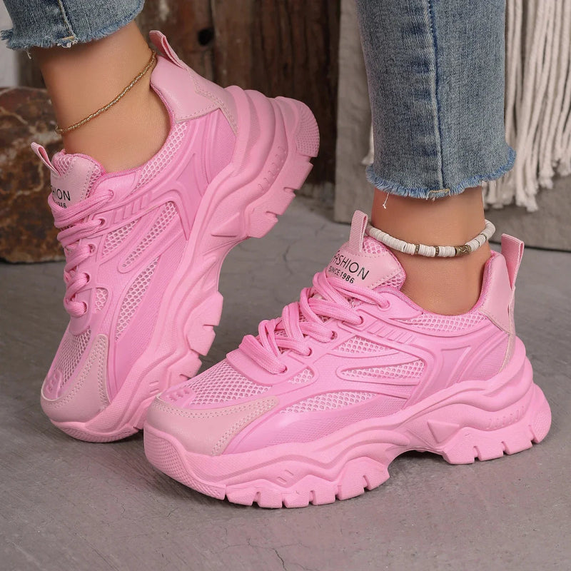 Pink sneakers worn with jeans on a neutral background