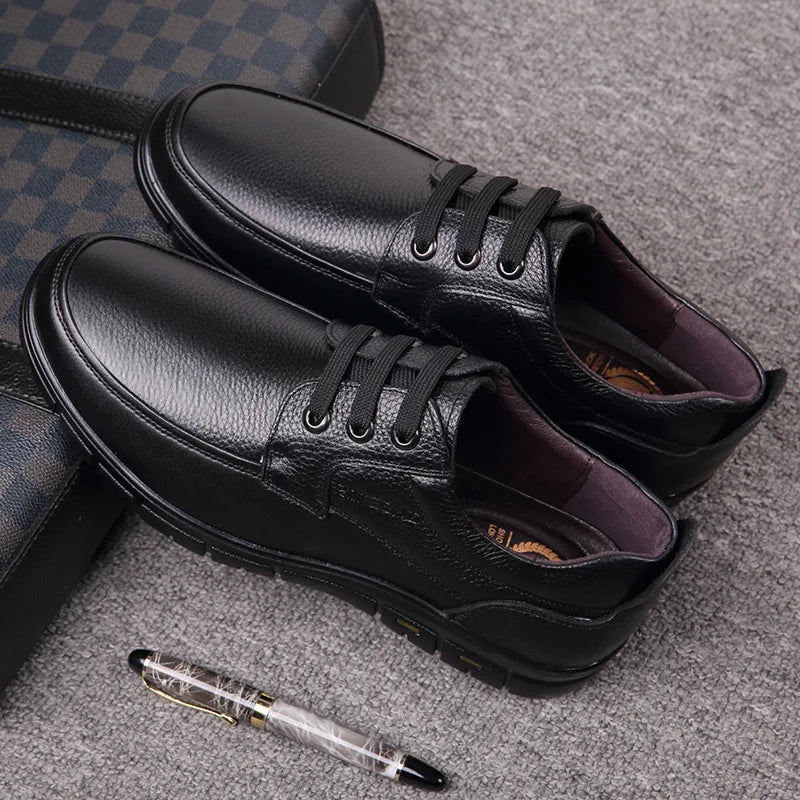 Black leather shoes on a textured surface with a pen beside them