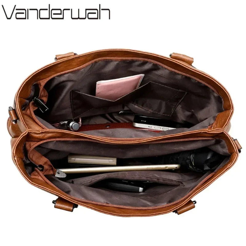 Brown leather bag with compartments and items on a white background, featuring the Vanderwah brand.