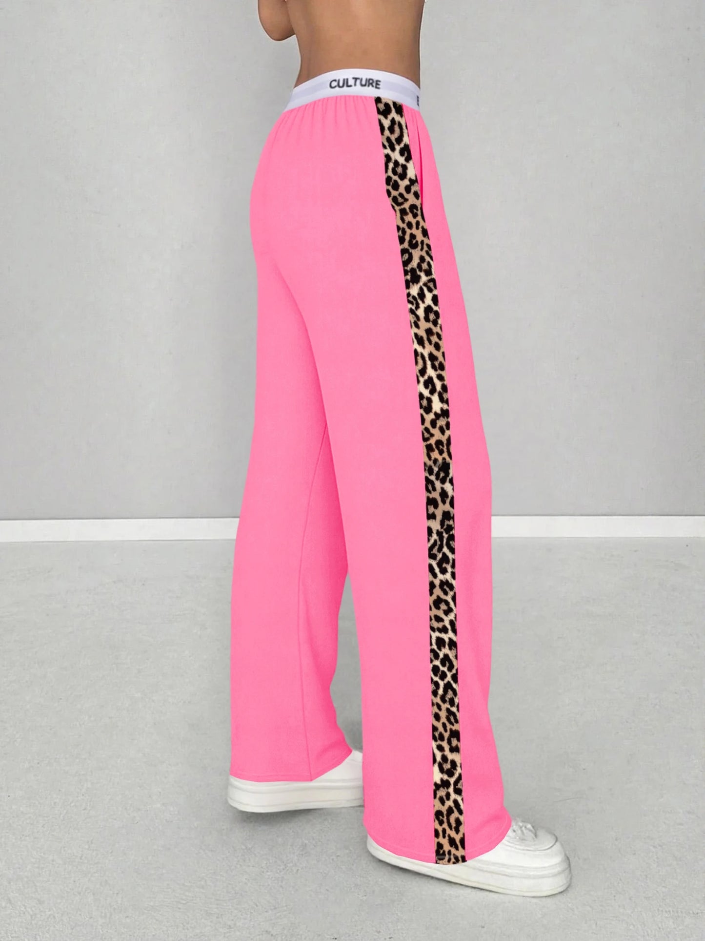 Pink sweatpants with leopard print side panels on a gray background