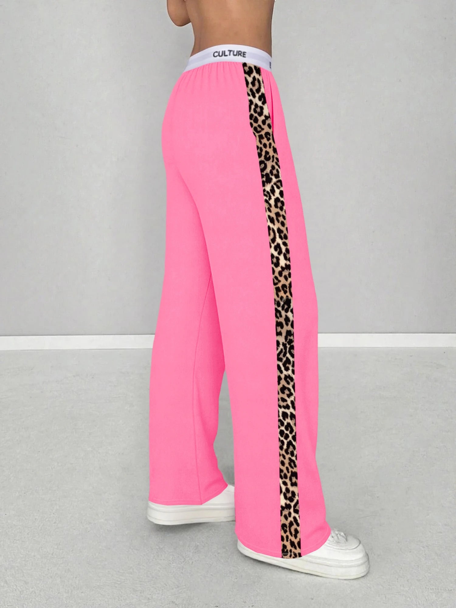 Pink sweatpants with leopard print side panels on a gray background